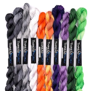 May include: Eight skeins of embroidery floss in various ombre colour combinations, including grey, white, orange, purple, and green. Each skein is labelled "THREADWORX" and "Hand Overdyed Floss".