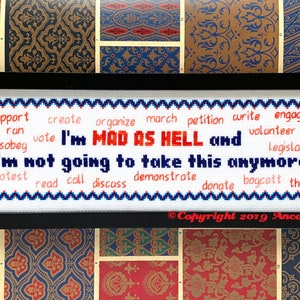 May include: White cross-stitch embroidery with a red and blue border. The text reads "I'm MAD AS HELL and I'm not going to take this anymore."  The text is surrounded by a list of action verbs in blue and red.