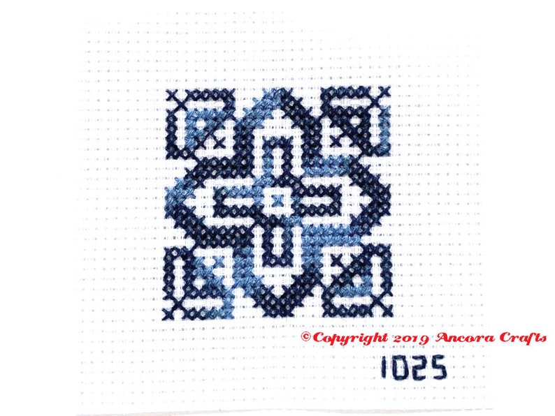ThreadworX 1025 Variegated Embroidery Floss Blue Navy thread has a repeating gradient of medium to dark navy blues and is shown here stitched in a geometric cross stitch pattern.