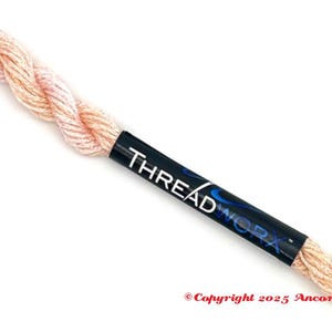 May include: A spool of Thread Work embroidery floss in a light peach color. The black label displays the brand name in white. The thread is twisted and angled across a white background. Copyright 2025 Ancora Crafts is printed at the bottom.