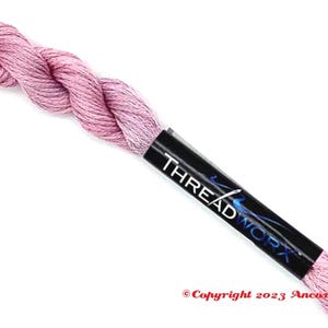 Peut inclure: Une pelote de fil à broder rose avec une étiquette noire sur laquelle est inscrit "THREADWORX".