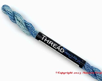 May include: A spool of blue and silver metallic thread. The label reads "THREADWORX" in white text on a black background. The thread is labeled "Kreink Tapestry #12 Braid - Artisan Dyed."