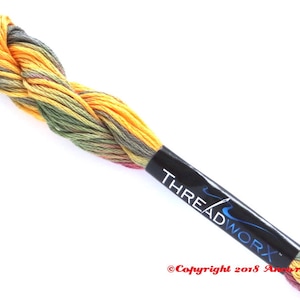 May include: A skein of embroidery floss in shades of yellow, green, and red. The floss is twisted together and has a black label with the text "THREADWORX" and a copyright notice.