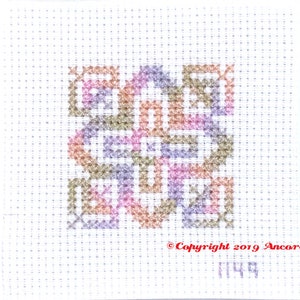 ThreadworX 1149 Variegated Rainbow Embroidery Floss Rainbow Fairy thread has a repeating gradient of soft pink, orange, green, and blue-purple, and is shown here stitched in a geometric cross stitch pattern.