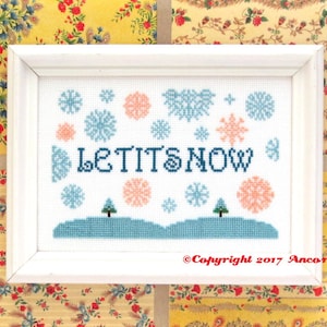 Könnte beinhalten: Weiß gerahmte Kreuzstich-Stickerei mit blauen und rosa Schneeflocken und dem Text "Let It Snow".