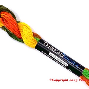 May include: A skein of hand-overdyed floss in shades of green, yellow, orange, and red. The floss is labeled "THREADWORX Hand Overdyed Floss Approximately 20 yards - 100% Cotton Copyright 2023"
