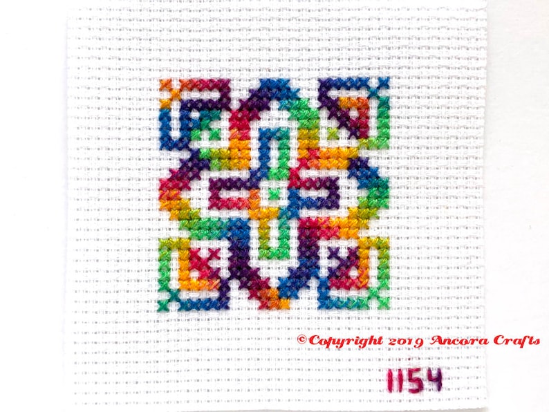 This ThreadworX 1154 rainbow embroidery floss is a gorgeous variegated blend of bright pink, orange, yellow, green, blue, and purple, and is shown here stitched in a geometric cross stitch pattern.