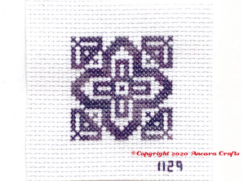 ThreadworX 1129 Variegated Embroidery Floss Merlot thread has a repeating gradient of dusky medium and dark purples and is shown here stitched in a geometric cross stitch pattern.