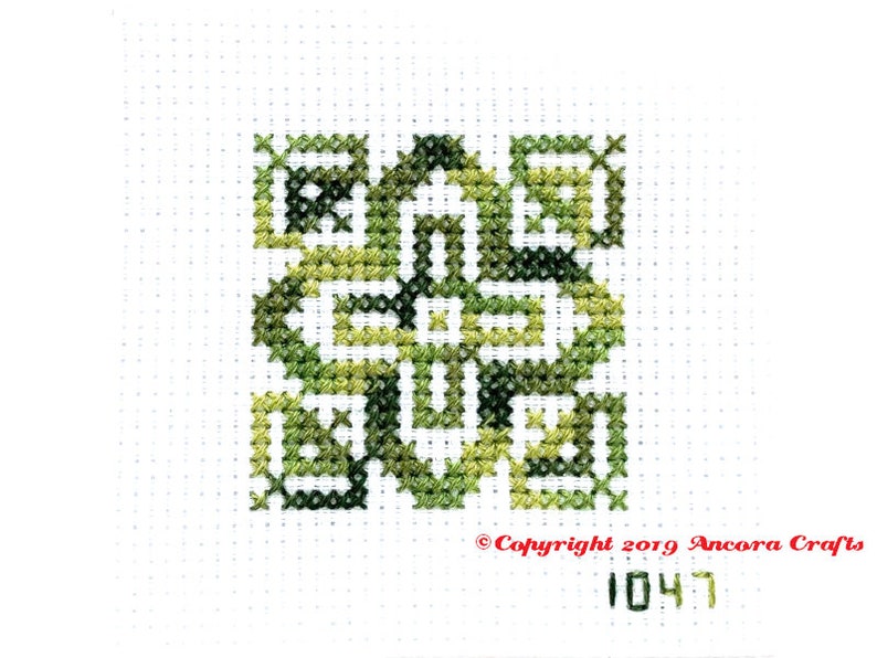 ThreadworX 1047 Variegated Embroidery Floss Tropical Green thread has a repeating gradient of tropical greens and is shown here stitched in a geometric cross stitch pattern.