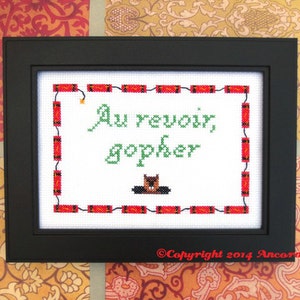 May include: A framed cross-stitch design featuring a gopher and the text "Au revoir, gopher" surrounded by red and black firecrackers. The bottom of the frame reads "Copyright 2014 Ancona Crafts".