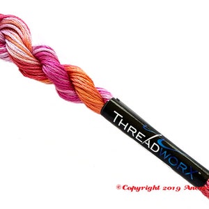 May include: A skein of pink, orange and white embroidery floss with a black label that reads "THREADWORK" and "Copyright 2019 Anchor Crafts".