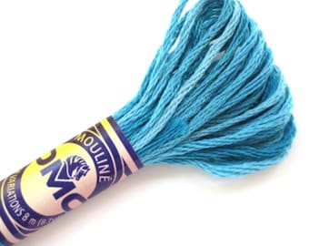 Puede incluir: Un ovillo de hilo de bordar DMC de color azul claro. El hilo está enrollado alrededor de un carrete de cartón con una etiqueta blanca que dice "DMC Mouline" y tiene un logotipo de caballo. La etiqueta también dice "Variations 8 m (8 yds)".
