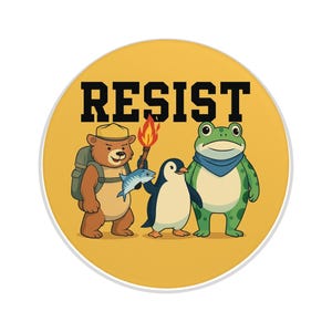May include: A round, yellow button with the word "RESIST" in black block letters. The button features cartoon illustrations of a bear with a backpack, a penguin, and a frog. The bear holds a fish, the penguin stands next to a torch, and the frog wears a blue scarf.