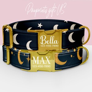 May include: Two personalized dog collars. The collars are navy blue with a celestial pattern of moons and stars. Each collar has a gold buckle with a name and phone number. The text "Pawprints gift US" is in the background.