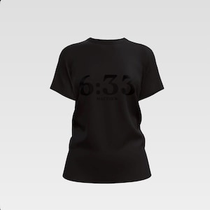 Puede incluir: Camiseta negra de cuello redondo con el texto "6:33" y la palabra "Matthew" impresa en un tono oscuro. La camiseta es de color negro liso y tiene mangas cortas.