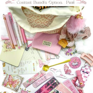 May include: A selection of pink stationery and accessories, including pens, lip balm, bookmarks, and a small pink corduroy pouch. The items are arranged on a white surface, with the text "Content Bundle Option: Pink" at the top.