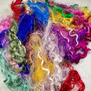 May include: A vibrant assortment of colorful craft fibers. The image showcases a mix of textures and hues, including red, blue, green, yellow, pink, and purple. The fibers appear to be silk or a similar material, ideal for various crafting projects.