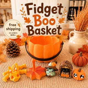 May include: A collection of orange and brown fidget toys including a pumpkin-shaped bucket, a dragon figure, a star-shaped spinner, a frog wearing a witch hat, a small house-shaped container, and a knitted pumpkin, all arranged on a textured surface.