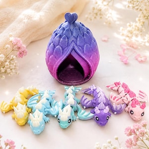 May include: A purple and blue gradient dragon egg with a heart-shaped topper, accompanied by five small articulated dragon figurines in yellow, light blue, teal, purple, and pink, each featuring white accents and detailed scale textures.