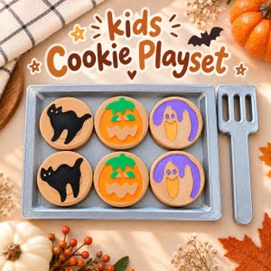 May include: A kids Cookie Playset featuring a silver rectangular tray and a matching spatula. The tray holds six round tan cookies decorated with black cats, orange jack-o'-lanterns, and purple ghosts. The text kids Cookie Playset is visible.