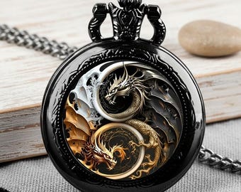 May include: Black pocket watch with a detailed dragon design. The watch features a black case and chain, with a dragon illustration in gold, silver, and black. The watch has a crown at the top.