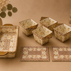 May include: A ceramic kitchen set featuring one rectangular baking dish with handles, three square bowls with handles, and two rectangular flat plates. Each piece is cream-colored with a brown and gold floral pattern and geometric borders.