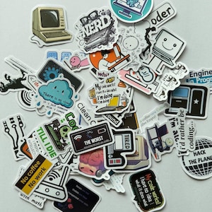 May include: A selection of vibrant stickers featuring computer and coding motifs. Designs include vintage computers, coding icons, and witty phrases such as "NERD," "THE WORST," and "No coffee No work." Perfect for laptops, notebooks, or tech accessories.