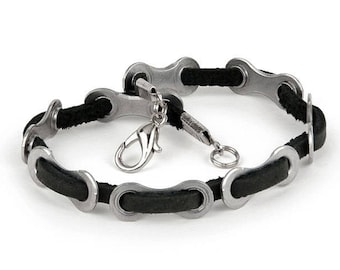 May include: A black leather bracelet with silver bike chain links and a silver clasp.