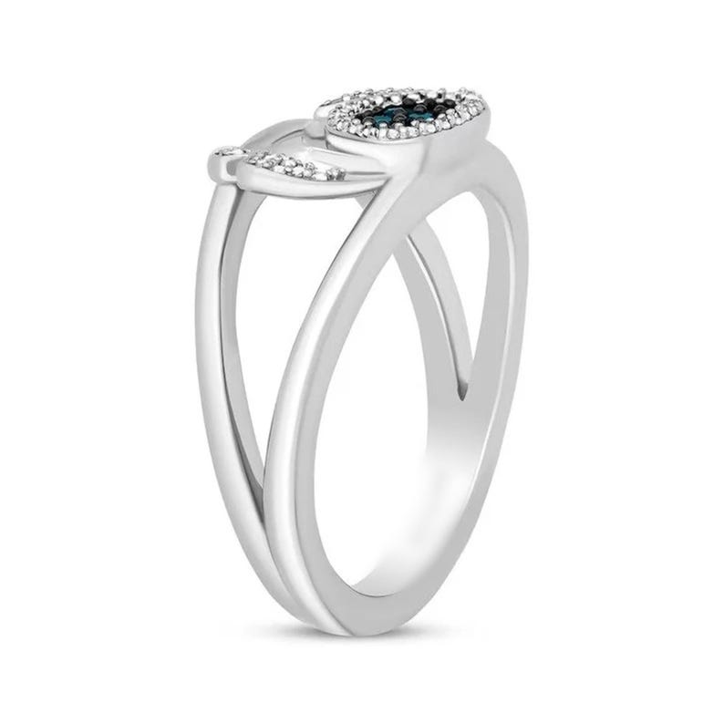 Op de afbeelding: Een zilveren ring met een uniek ontwerp. De ring heeft een centrale ovale zetting met een donkerblauwe steen omringd door kleine, heldere stenen. De band splitst zich in twee sierlijke rondingen.
