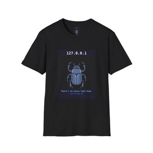 Puede incluir: Camiseta negra con un diseño de escarabajo azul pixelado y el texto "127.0.0.1". Debajo, se lee "There's no place like home. Let It Be It."