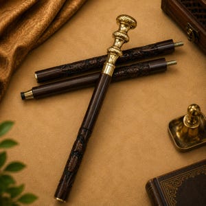 Puede incluir: Un bastón plegable con un eje de madera marrón oscuro con intrincadas tallas florales y un mango de metal pulido en tono dorado. El mango tiene un diseño redondeado y escalonado, y los segmentos del eje se conectan mediante tornillos metálicos.