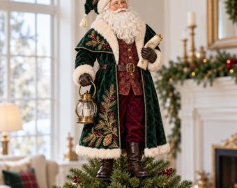 May include: A Santa Claus figurine standing atop a Christmas tree. The figure wears a dark green velvet coat with cream faux fur trim, gold embroidery, and a red patterned vest. He holds a scroll in one hand and a gold lantern in the other.