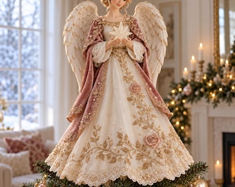 May include: A decorative angel tree topper featuring large feathered wings, a cream-colored gown with gold floral embroidery, and a dusty rose velvet cape. The figure holds a luminous white star and is adorned with pearl accents and roses.