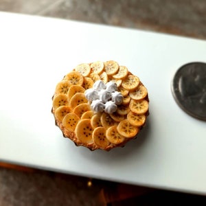 Tarta de crema de plátano en miniatura de arcilla polimérica para casa de muñecas con crema batida