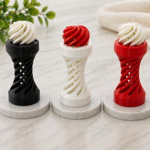 May include: Three decorative bottle stoppers in black, white, and red. Each stopper has a spiral design and a swirl-shaped top. They are displayed on round, marble-effect bases, showcasing a modern and artistic design.