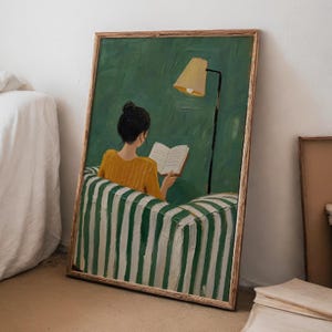 Puede incluir: Un cuadro al óleo enmarcado que muestra a una persona con el pelo oscuro recogido en un moño, vistiendo una blusa amarilla mostaza, sentada en un sillón de rayas verdes y blancas mientras lee un libro abierto. Una lámpara de pie beige al lado.
