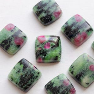Peut inclure: Huit cabochons de forme carrée présentant une surface polie avec un motif marbré d'inclusions vert clair, vert foncé et noires, rehaussé par des taches arrondies distinctes de rose magenta vif sur chaque pierre individuelle.