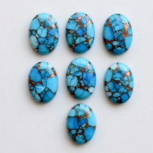 Puede incluir: Siete cabujones de forma ovalada con un vibrante color azul cielo y vetas intrincadas de color marrón oscuro y cobre metálico. Cada piedra muestra un patrón único tipo mosaico de segmentos fracturados con un acabado pulido.