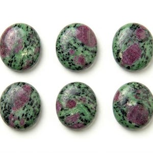 May include: Six round, polished cabochons of zoisite with ruby inclusions. Each stone features a mottled green base with distinct, opaque magenta-red patches and small, scattered black mineral flecks throughout the smooth, rounded surfaces.