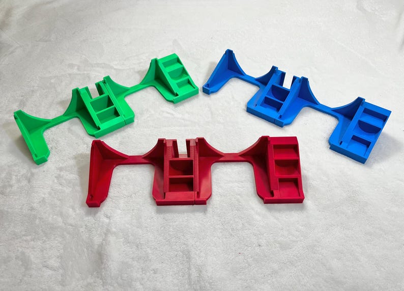 May include: Four plastic, multi-colored objects. The objects are in green, blue, and red. Each object has a unique shape with a series of steps and a central support structure. The objects are likely for supporting or holding other items.