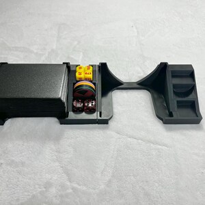 May include: Black plastic tabletop game organizer with compartments for cards, dice, and other game accessories. The organizer has a rectangular card holder, a dice tray, and a curved section for additional items.
