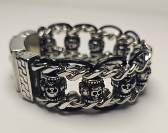 May include: A silver-toned bracelet with a chain link design. The bracelet features skull accents and a rectangular clasp. The links are connected by a black band. The bracelet is approximately 8 inches in length.