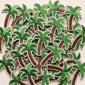 May include: A collection of embroidered palm tree patches. Each patch features a brown trunk, green fronds, and a white border. The patches are scattered across a neutral background, creating a tropical theme.