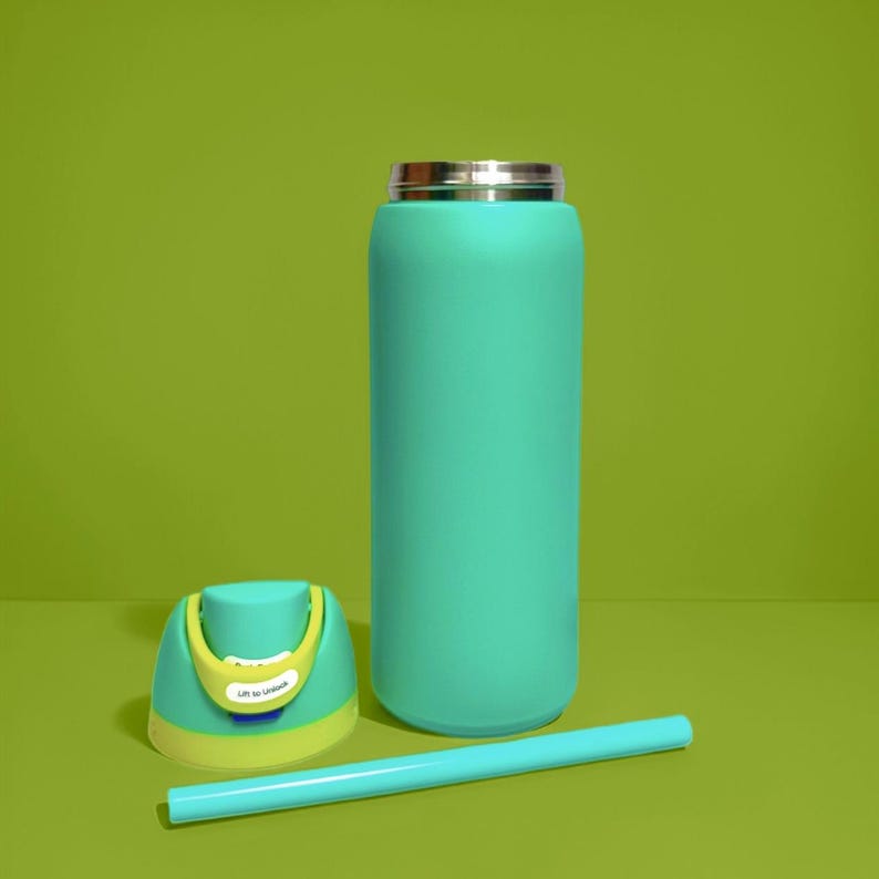 Puede incluir: Una botella de agua aislada de color turquesa con tapa plateada, pajita a juego y tapa separada. La tapa es turquesa con detalles amarillos y blancos. Las palabras "Lift to Unlock" est&aacute;n impresas en la tapa.