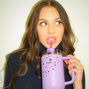 Peut inclure: Une tasse Stanley lilas avec une poign&eacute;e et une paille. La tasse est orn&eacute;e d'un motif d'&eacute;toiles de diff&eacute;rentes couleurs. Le logo Stanley est visible sur le devant de la tasse.