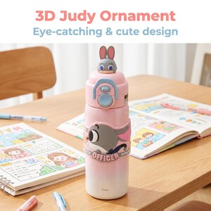 以下が含まれることがあります： 上部に3Dジュディ・ホップスの装飾が付いたピンク色のウォーターボトル。ボトルは、漫画のジュディ・ホップスのデザインと「OFFICER」の文字が特徴です。「3D Judy Ornament Eye-catching & cute design」というテキストが上部にあります。