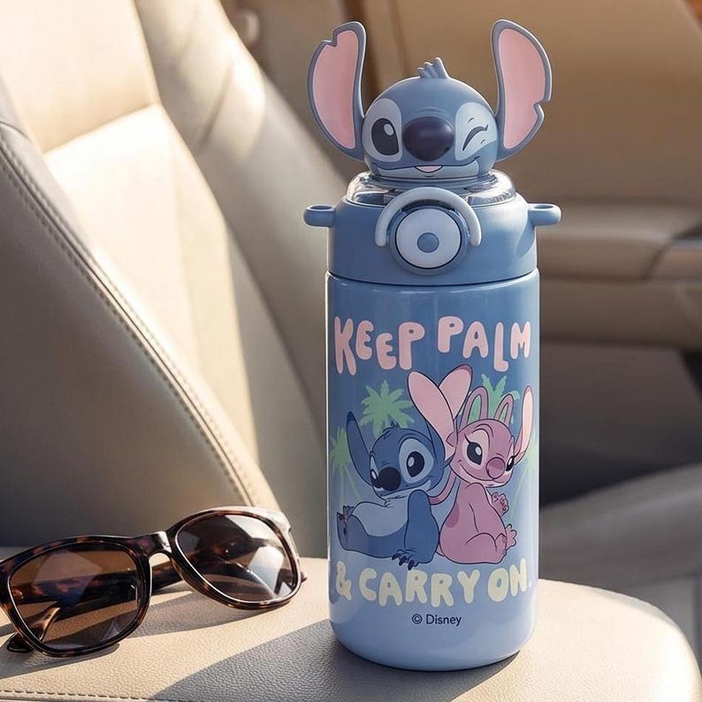 Op de afbeelding: Een blauwe waterfles met een Stitch-personageontwerp op het deksel. De fles heeft de tekst "KEEP PALM & CARRY ON" en een afbeelding van Stitch en Angel. Een zonnebril met schildpadmotief ligt ernaast.
