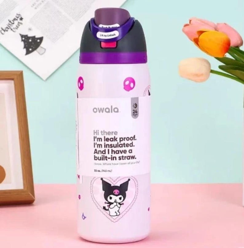 May include: A white and purple Owala water bottle with a black and purple lid. The bottle has a cartoon design and the text "Hi there I'm leak proof. I'm insulated. And I have a built-in straw." The bottle holds 946 ml.