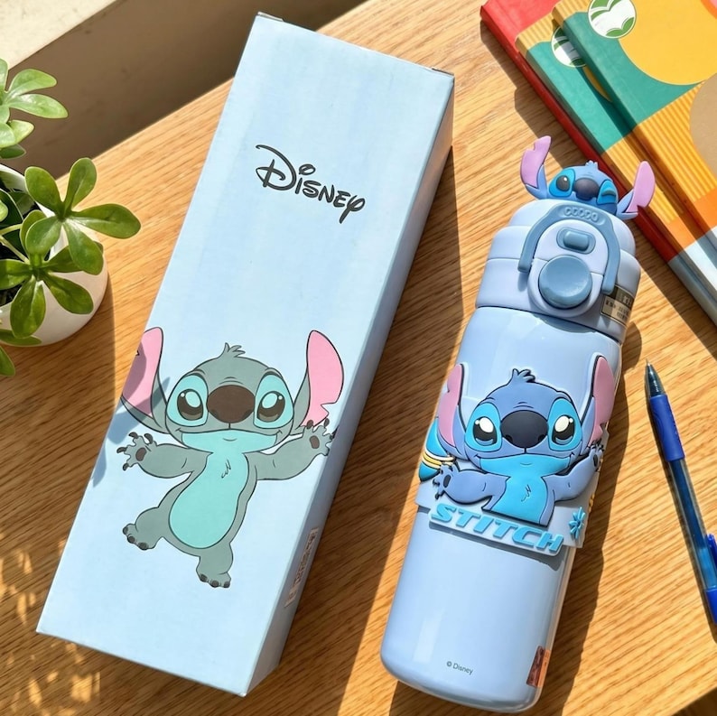 以下が含まれることがあります： ディズニーをテーマにした水色のウォーターボトルと、キャラクターのスティッチが描かれたお揃いの箱。ボトルは青い蓋とスティッチのデザイン。箱にはディズニーのロゴとスティッチのグラフィック。木製の表面にあります。