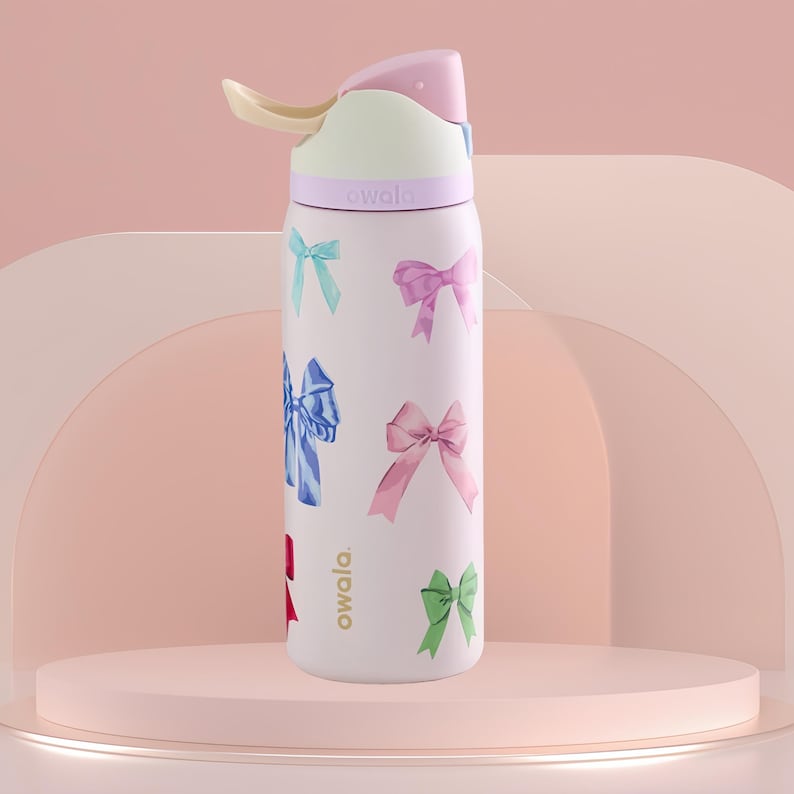 May include: A light pink Owala water bottle featuring a bow pattern in pastel shades. The bottle has a pink, white, and yellow lid with a straw. The word "owala" is printed on the bottle. This insulated bottle is designed for hydration.